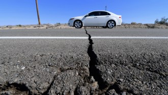 A photo of a car driving over a crack on a highway.