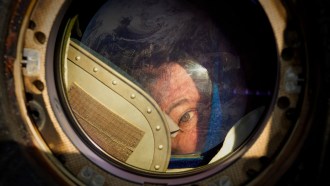 Cady Coleman looks through a circular window on the ISS.